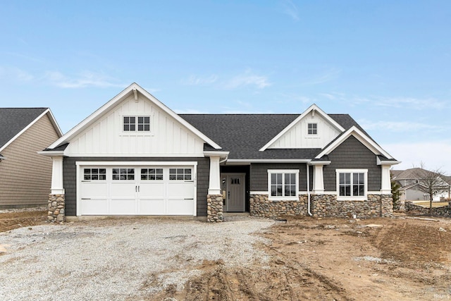 view of front of home featuring a garage, a shingled roof, dirt driveway, stone siding, and board and batten siding