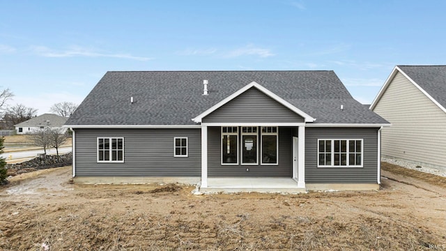 back of property with a shingled roof and a patio area