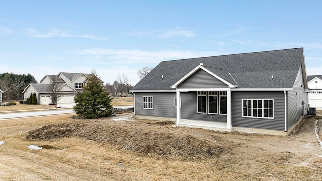 rear view of house featuring roof with shingles, a patio, and central AC unit