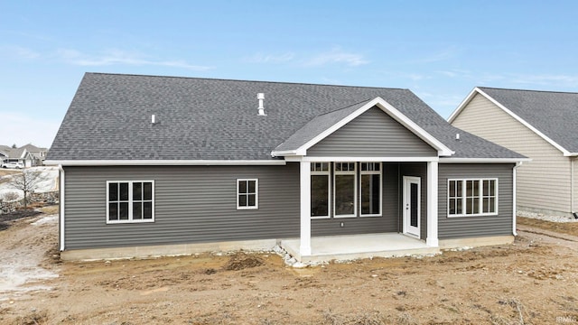 rear view of house featuring a patio area and roof with shingles