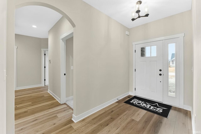 entrance foyer with arched walkways, light wood-type flooring, and baseboards