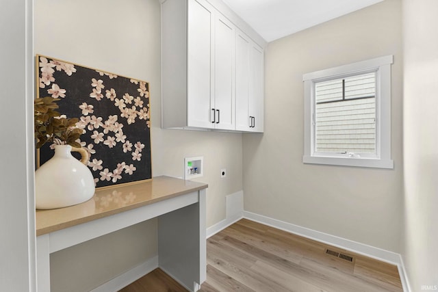 clothes washing area with visible vents, baseboards, cabinet space, light wood finished floors, and electric dryer hookup