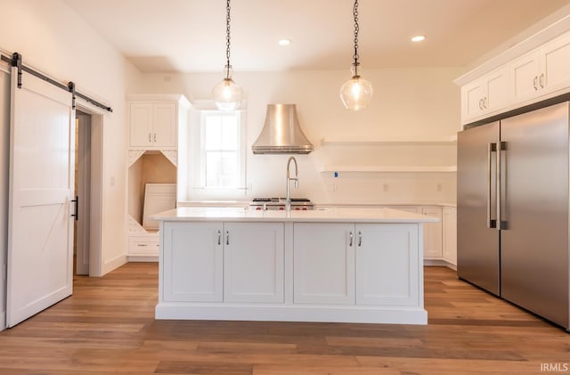 kitchen featuring a barn door, white cabinetry, light countertops, and stainless steel built in fridge