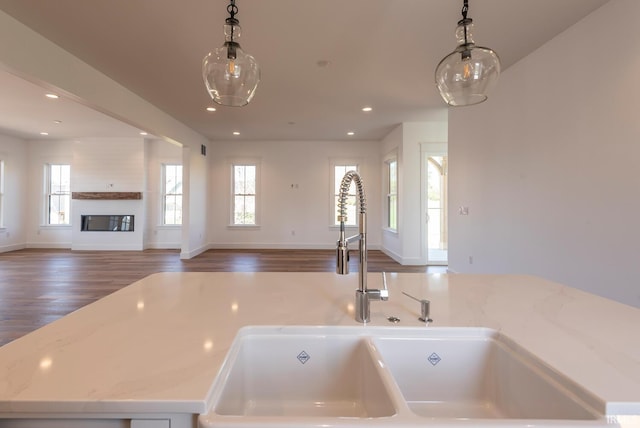 kitchen with pendant lighting, wood finished floors, open floor plan, recessed lighting, and a large fireplace