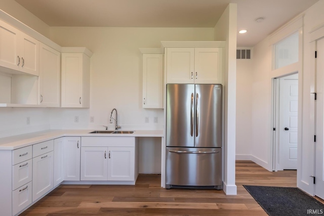 kitchen featuring visible vents, a sink, freestanding refrigerator, white cabinets, and light wood finished floors