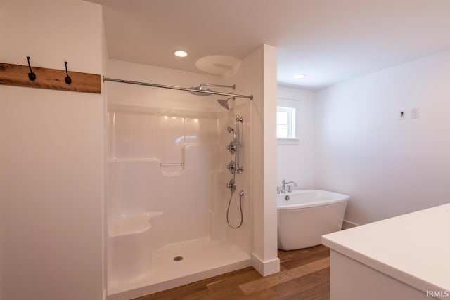 full bath with recessed lighting, a freestanding bath, walk in shower, and wood finished floors