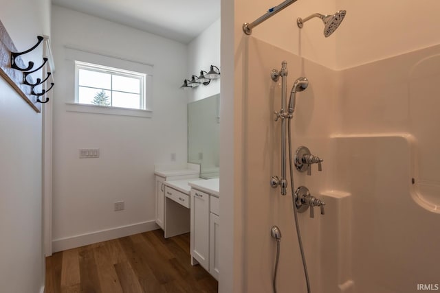 full bath with baseboards, walk in shower, wood finished floors, and vanity