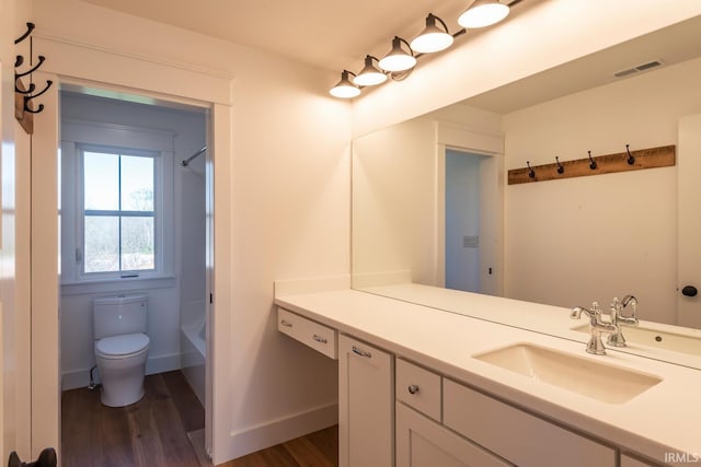 bathroom with visible vents, baseboards, toilet, wood finished floors, and vanity