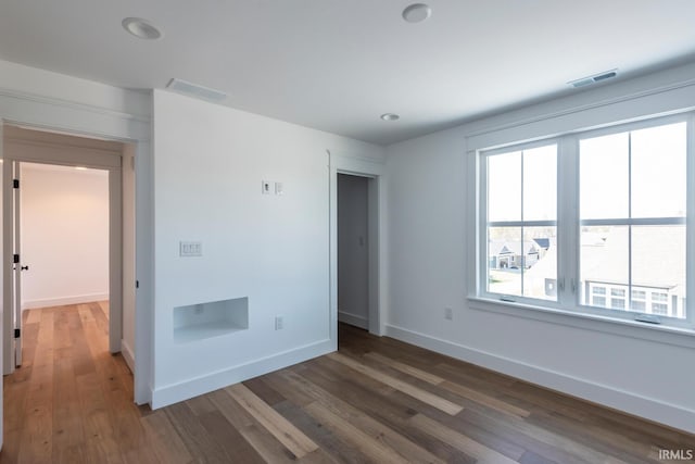 unfurnished bedroom featuring visible vents, baseboards, and wood finished floors