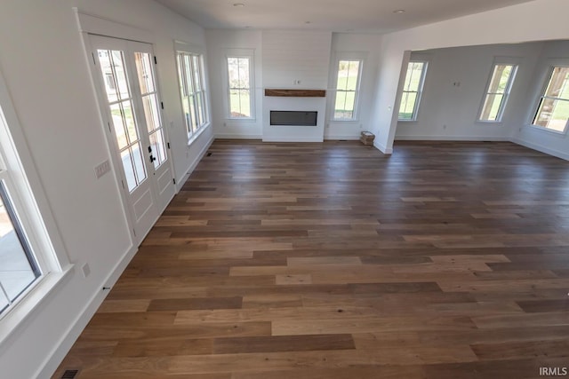 unfurnished living room with dark wood-type flooring, baseboards, and a large fireplace