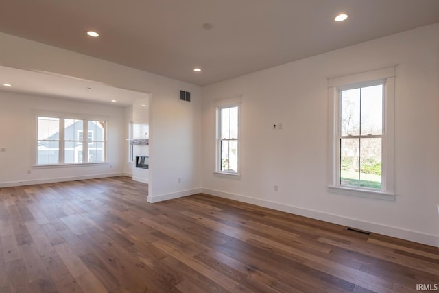 spare room with dark wood-type flooring, recessed lighting, and a healthy amount of sunlight