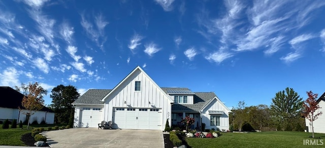 view of front facade with concrete driveway, a front lawn, board and batten siding, and a shingled roof