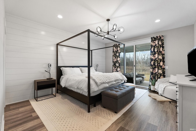 bedroom with wooden walls, wood finished floors, access to outside, a chandelier, and recessed lighting