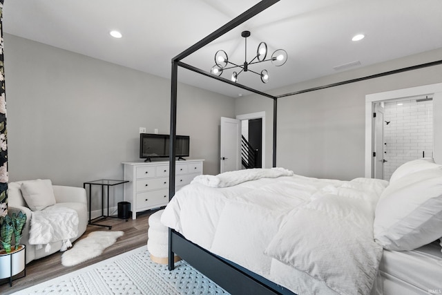 bedroom with ensuite bathroom, recessed lighting, wood finished floors, visible vents, and an inviting chandelier