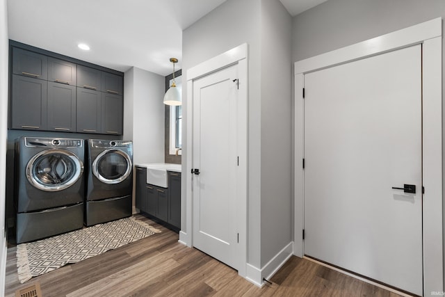 washroom with separate washer and dryer, a sink, visible vents, wood finished floors, and cabinet space