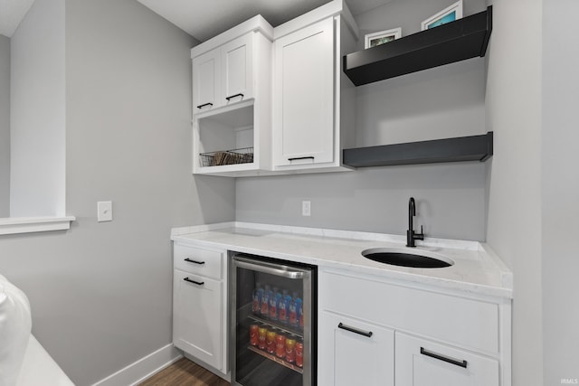 bar featuring beverage cooler, dark wood-style flooring, a sink, and baseboards