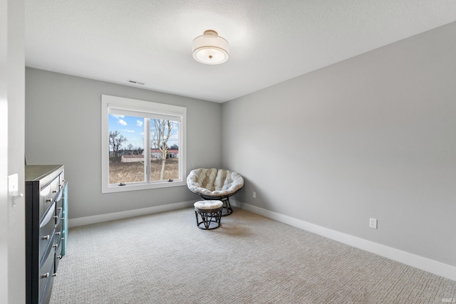 sitting room featuring carpet flooring, visible vents, baseboards, and a textured ceiling