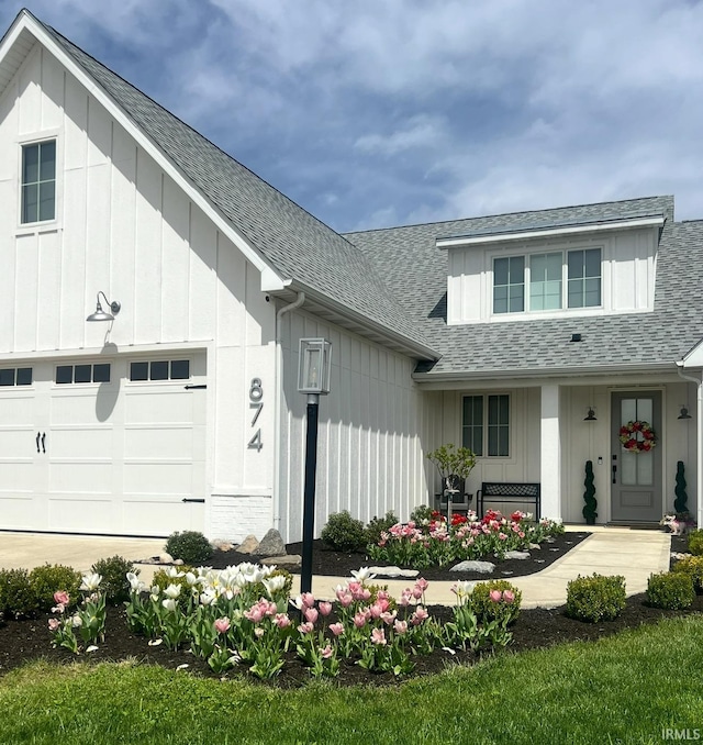 modern farmhouse with a garage, a shingled roof, and board and batten siding