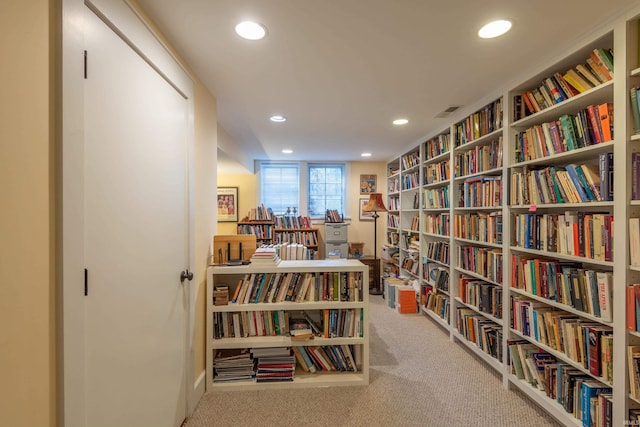 sitting room with recessed lighting, bookshelves, and carpet flooring