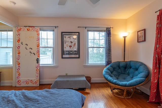 bedroom with a ceiling fan, wood-type flooring, multiple windows, and baseboards