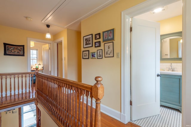 corridor featuring attic access, a healthy amount of sunlight, baseboards, and an upstairs landing