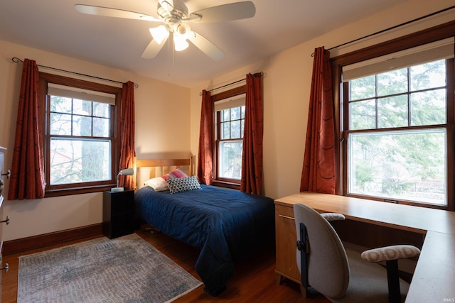 bedroom with baseboards, multiple windows, a ceiling fan, and wood finished floors