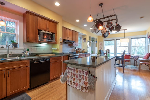 kitchen featuring stainless steel appliances, a sink, under cabinet range hood, and decorative backsplash