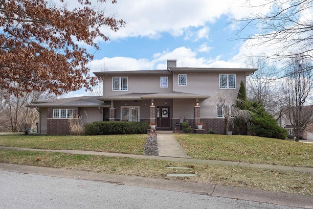 view of front facade featuring a porch, brick siding, a chimney, and a front yard