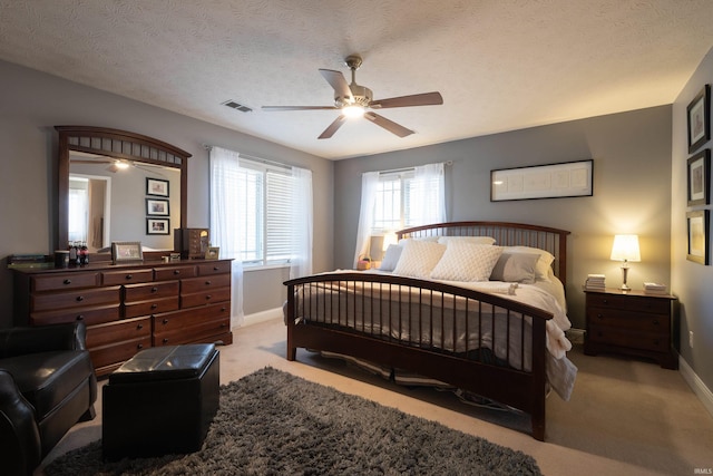 carpeted bedroom featuring visible vents, baseboards, a textured ceiling, and a ceiling fan