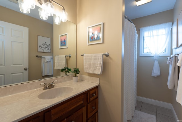 full bath with baseboards, a chandelier, vanity, and tile patterned flooring