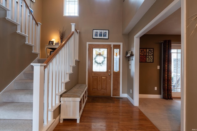 entrance foyer with stairs, baseboards, wood finished floors, and a towering ceiling