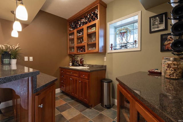 bar featuring a sink, indoor wet bar, baseboards, and hanging light fixtures