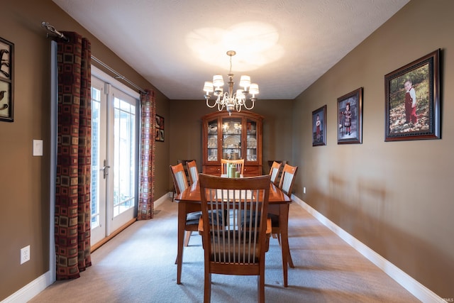 dining room featuring light carpet, french doors, baseboards, and an inviting chandelier