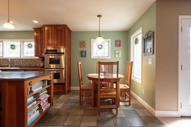 dining room featuring dark tile patterned floors, plenty of natural light, and baseboards