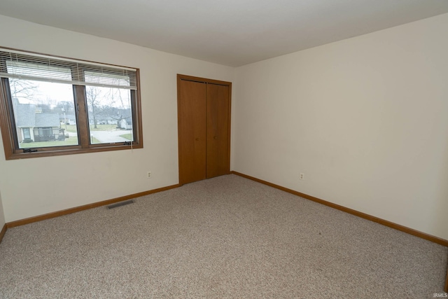 carpeted empty room featuring visible vents and baseboards