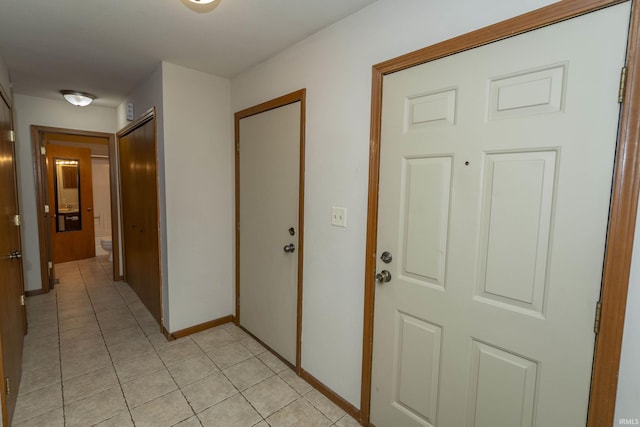 hallway with light tile patterned floors and baseboards