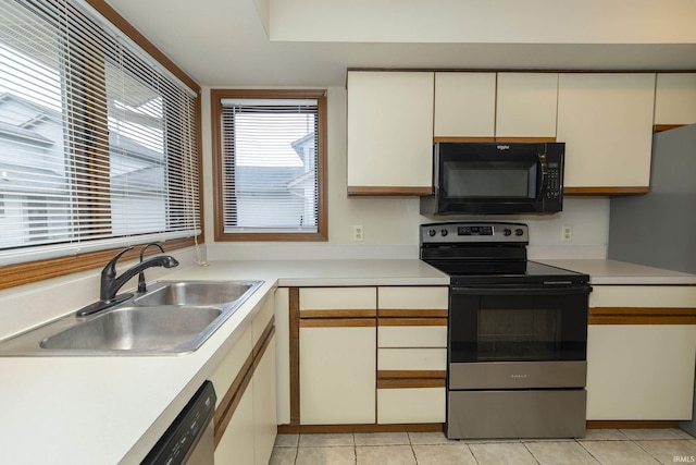 kitchen with light tile patterned floors, light countertops, appliances with stainless steel finishes, and a sink