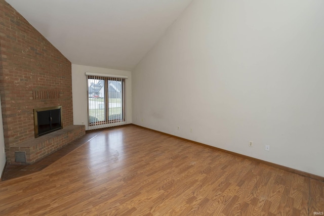 unfurnished living room with high vaulted ceiling, a fireplace, wood finished floors, visible vents, and baseboards