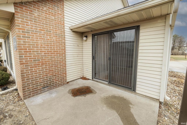 entrance to property with brick siding and a patio