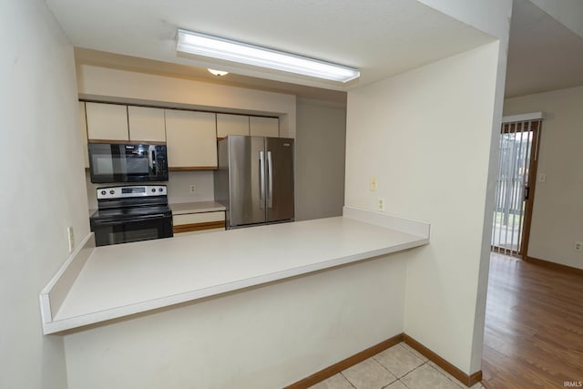 kitchen featuring appliances with stainless steel finishes, light countertops, a peninsula, and baseboards