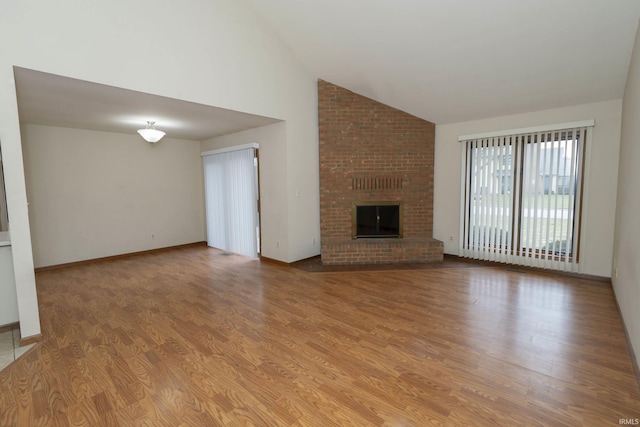 unfurnished living room featuring high vaulted ceiling, a brick fireplace, baseboards, and wood finished floors