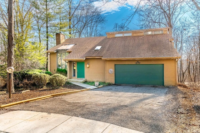 mid-century home featuring a garage, a chimney, aphalt driveway, and roof with shingles