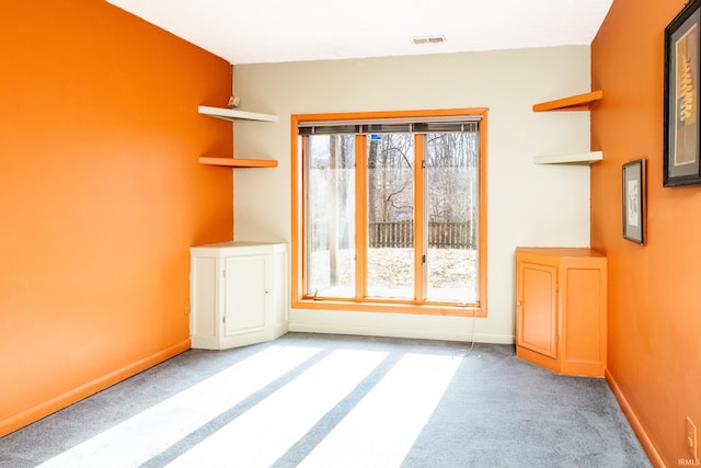 unfurnished room with carpet, visible vents, and baseboards