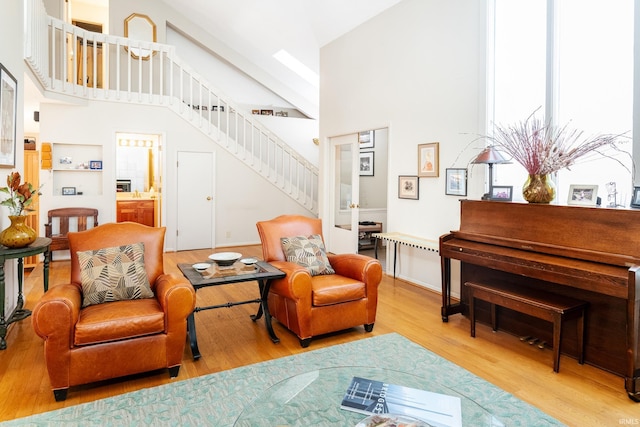 sitting room with high vaulted ceiling, stairway, and wood finished floors