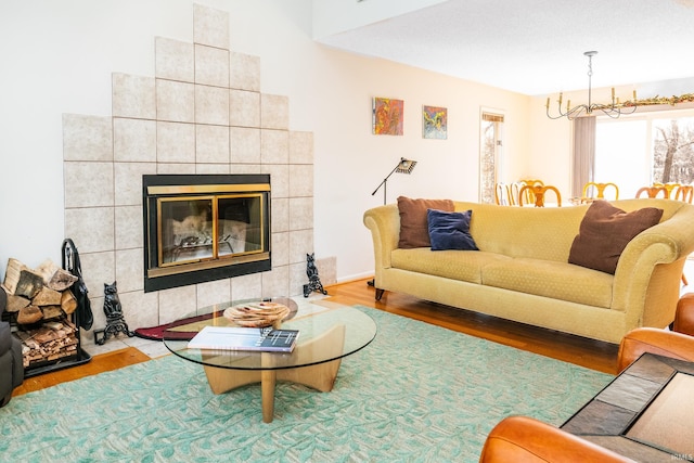 living area featuring a chandelier, a tiled fireplace, and wood finished floors