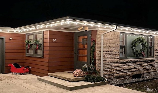 exterior entry at night featuring stone siding