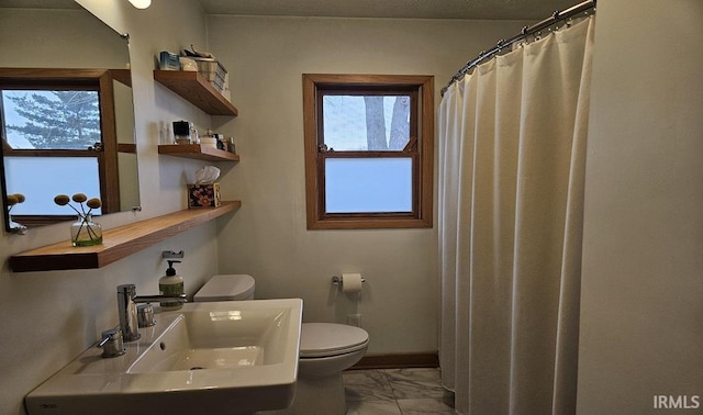 full bathroom featuring toilet, marble finish floor, baseboards, and a sink