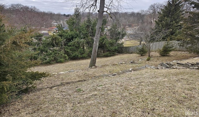 view of yard with a forest view and fence