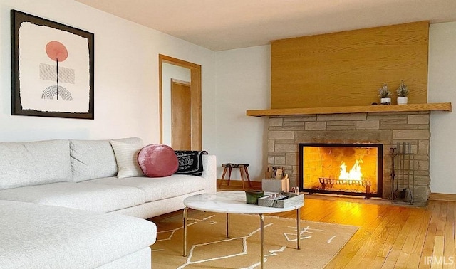 living room with hardwood / wood-style floors and a stone fireplace