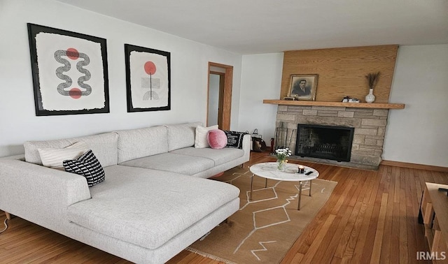 living area with a stone fireplace and wood-type flooring